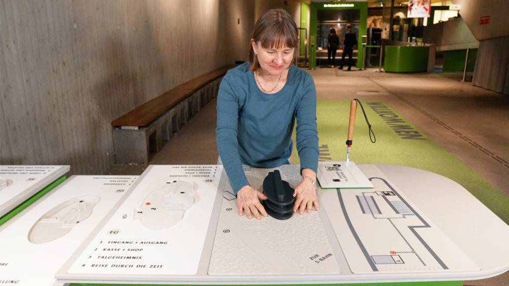Eine Frau mit Sehbehinderung ertastet ein Tastmodel zur Orientierung im Museum.