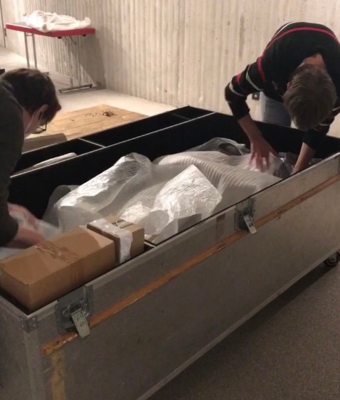 Praktikant und Volontär packen Ötzi in eine große Kiste.